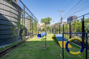 A fenced outdoor play area with a slide and climbing structures.