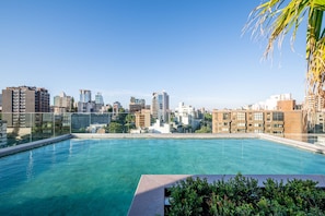 Una piscina en la azotea con vistas a un paisaje urbano, rodeada de edificios.
