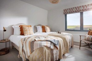 Ein Schlafzimmer mit zwei Betten, einem Fenster mit Blick, einem Nachttisch mit Lampe und einem Sessel.