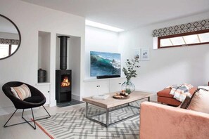 Ein modernes Wohnzimmer mit Kamin, einem an der Wand befestigten Fernseher und einer gemütlichen Sitzecke.