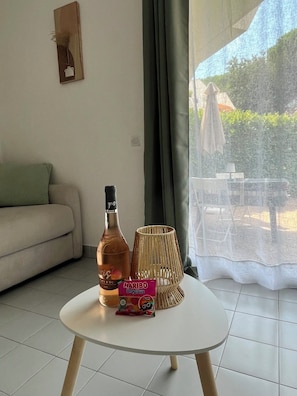 Un salon avec un canapé, une petite table sur laquelle se trouve une bouteille, une boîte de collations et un panier en osier.
