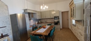 A kitchen with a wooden table, chairs, a refrigerator, and a microwave. - A renovated stone house with a view, ideal for quiet family moments (Galia)
