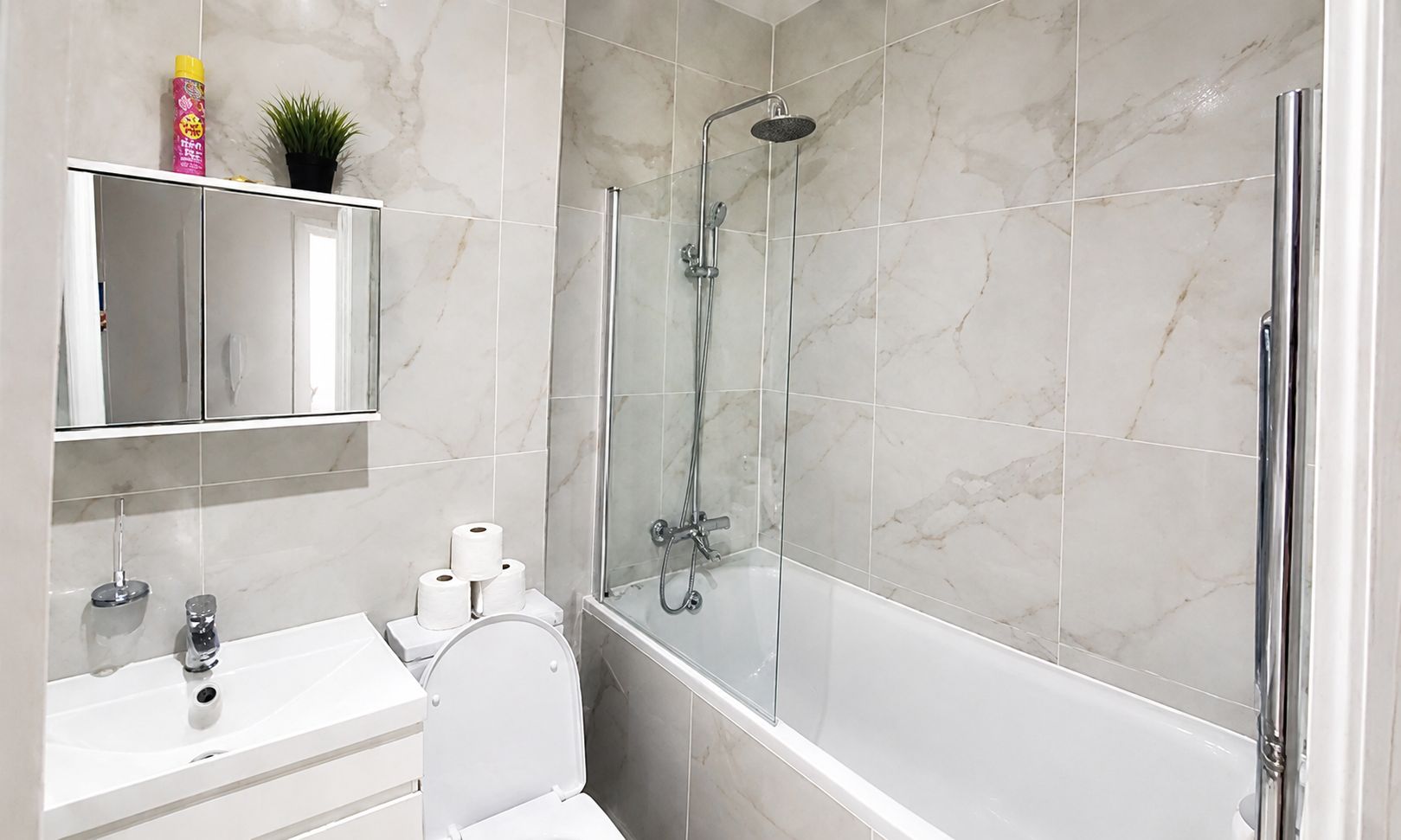 A modern bathroom with a glass-enclosed shower, a white sink, and a toilet.