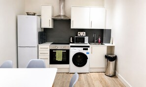 Una cocina compacta equipada con refrigerador, microondas, horno y lavadora.