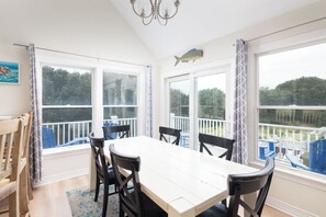 A dining area with a table and chairs, large windows with curtains, and a view of the outdoors. - Golf Views, Private Pool/Spa, Community Amenities! (Corolla)