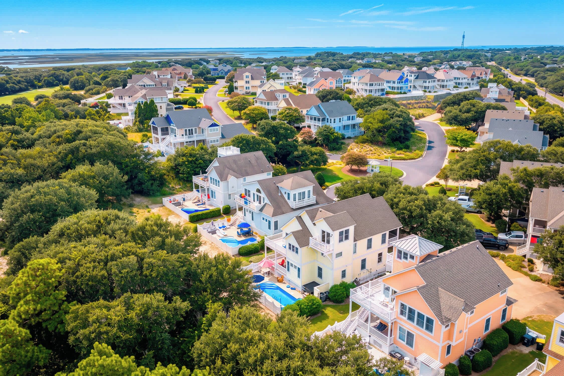 A residential area with houses, a swimming pool, and a view of the sea.