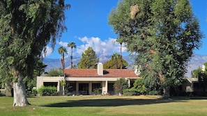 A two-story building with a red-tiled roof, surrounded by trees and a clear sky. - Spacious 3-bedroom condo in tranquil Rancho Mirage (Rancho Mirage)