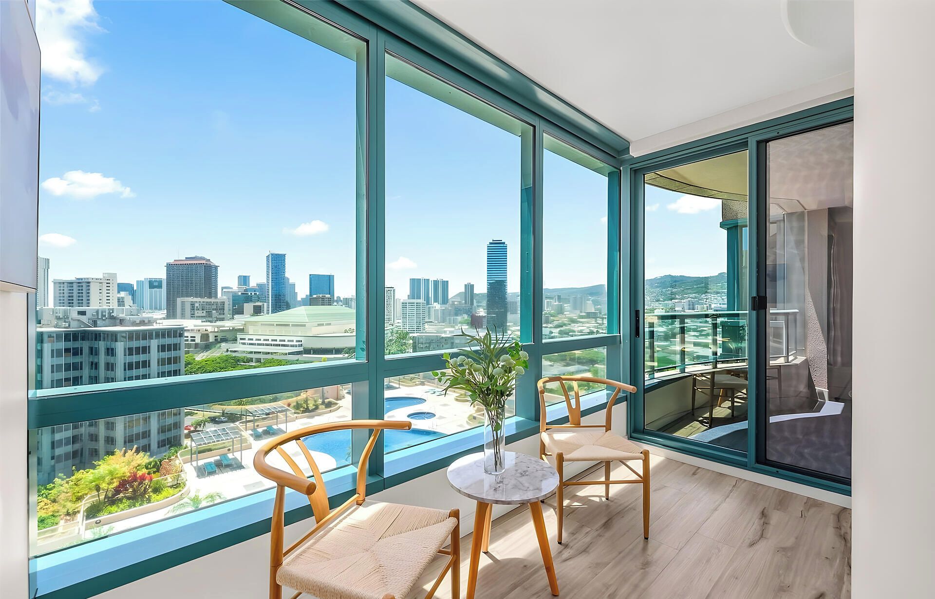 A balcony with a city view, two chairs, a small table, and a potted plant.