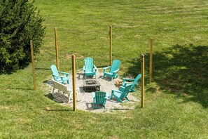 A circular outdoor seating area with chairs and a central fire pit surrounded by a fence.