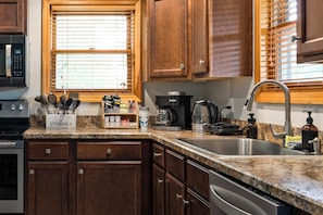 A kitchen with wooden cabinets, a granite countertop, a coffee maker, and a dishwasher.