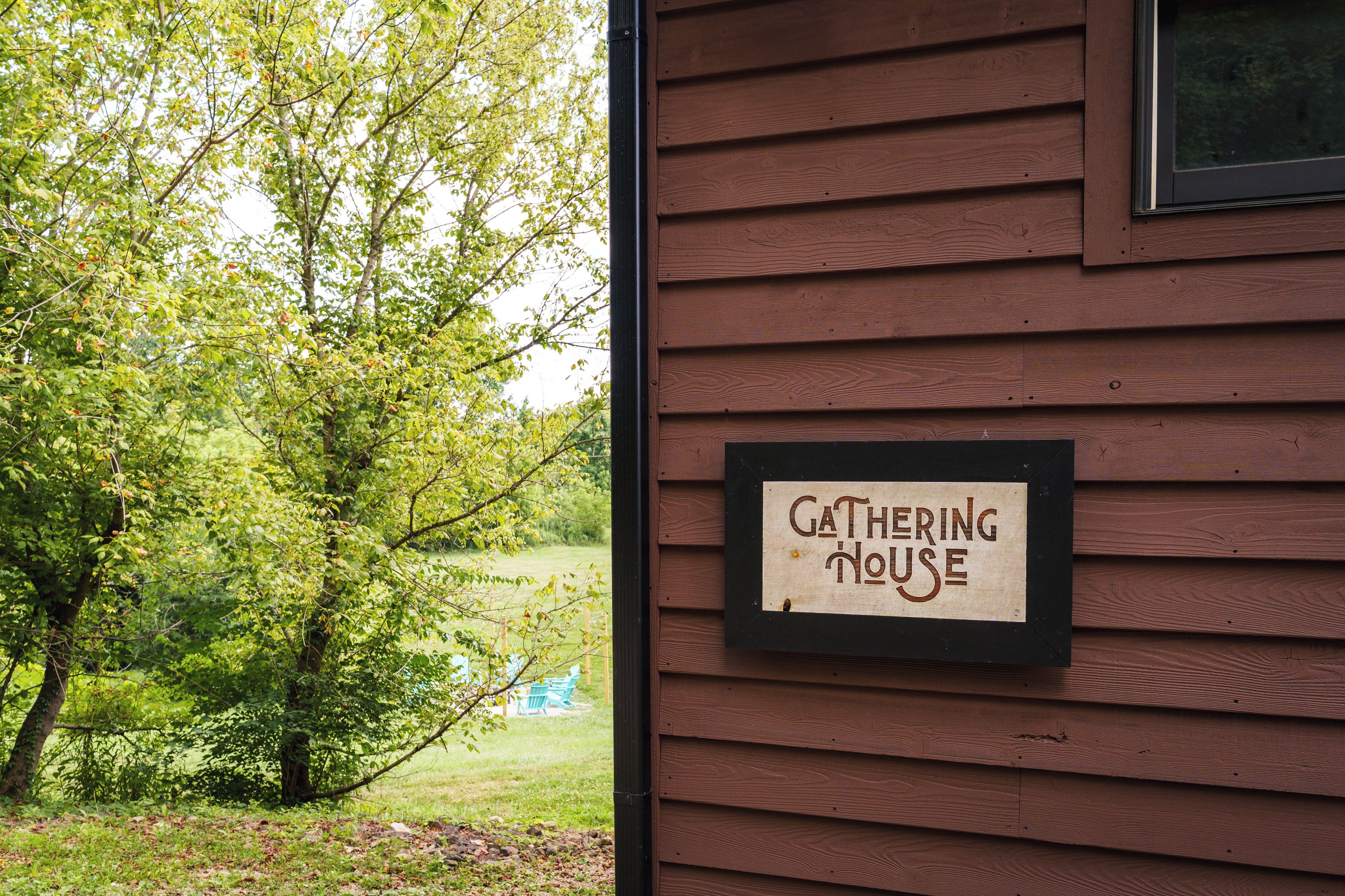 Pared exterior de madera con un letrero que dice 'Gathering House'.