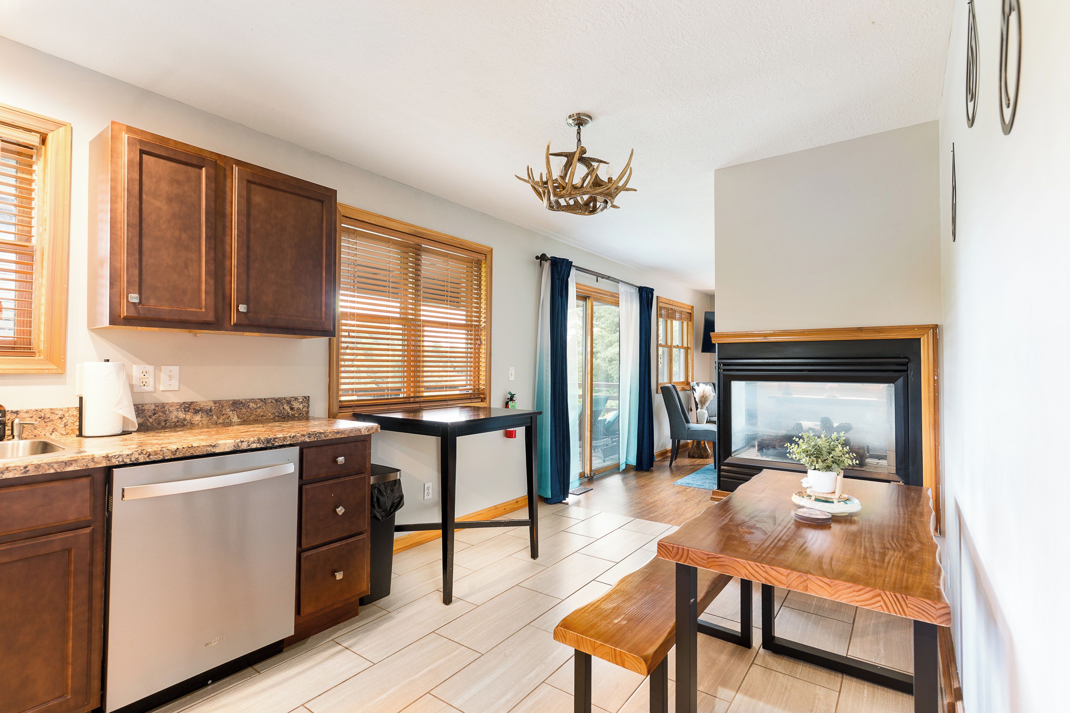 Una cocina moderna con armarios de madera, lavavajillas integrado, una mesa de comedor con bancos y vistas al exterior a través de amplios ventanales.