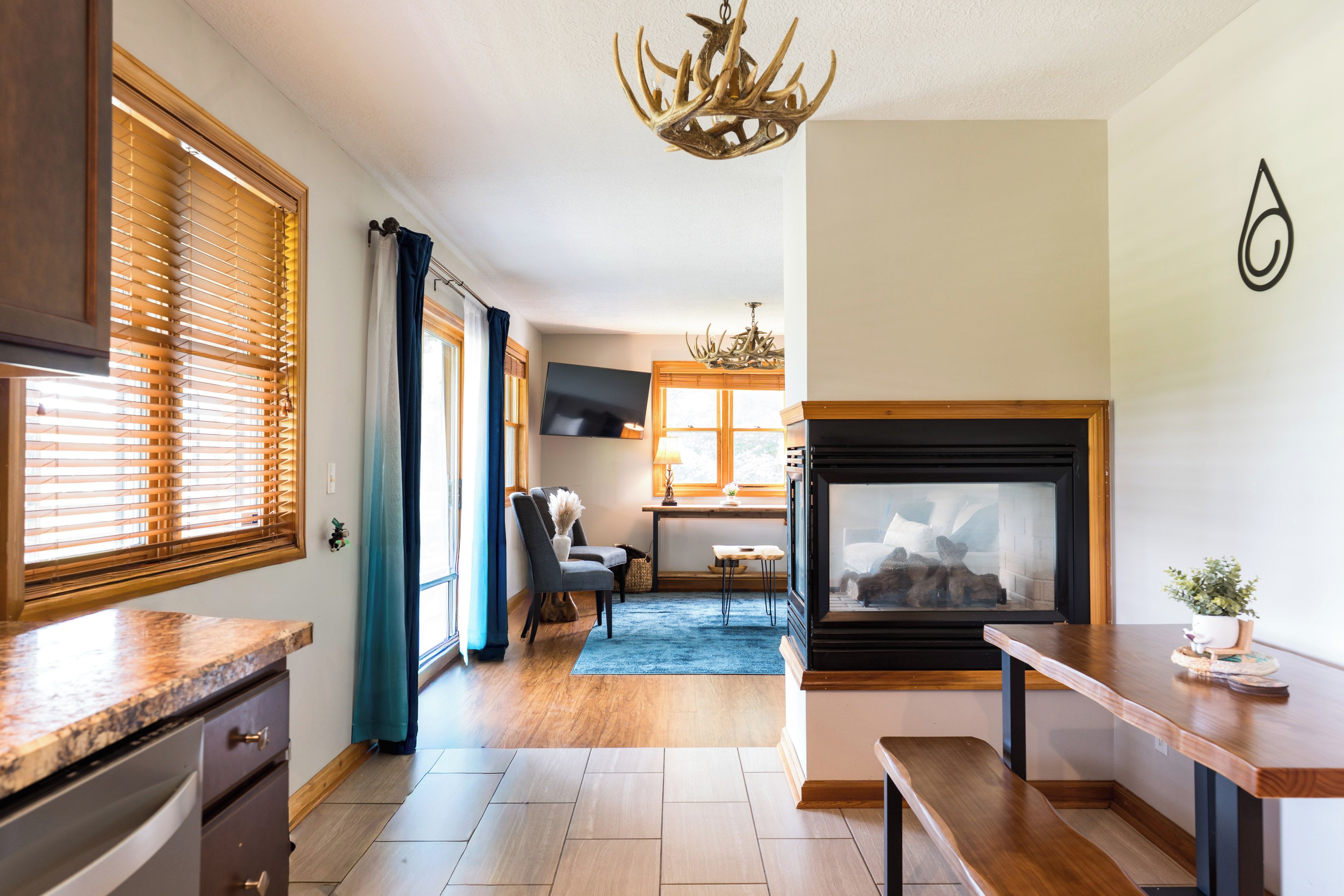 Una cocina moderna con chimenea, piso de madera y un comedor con vistas al exterior.