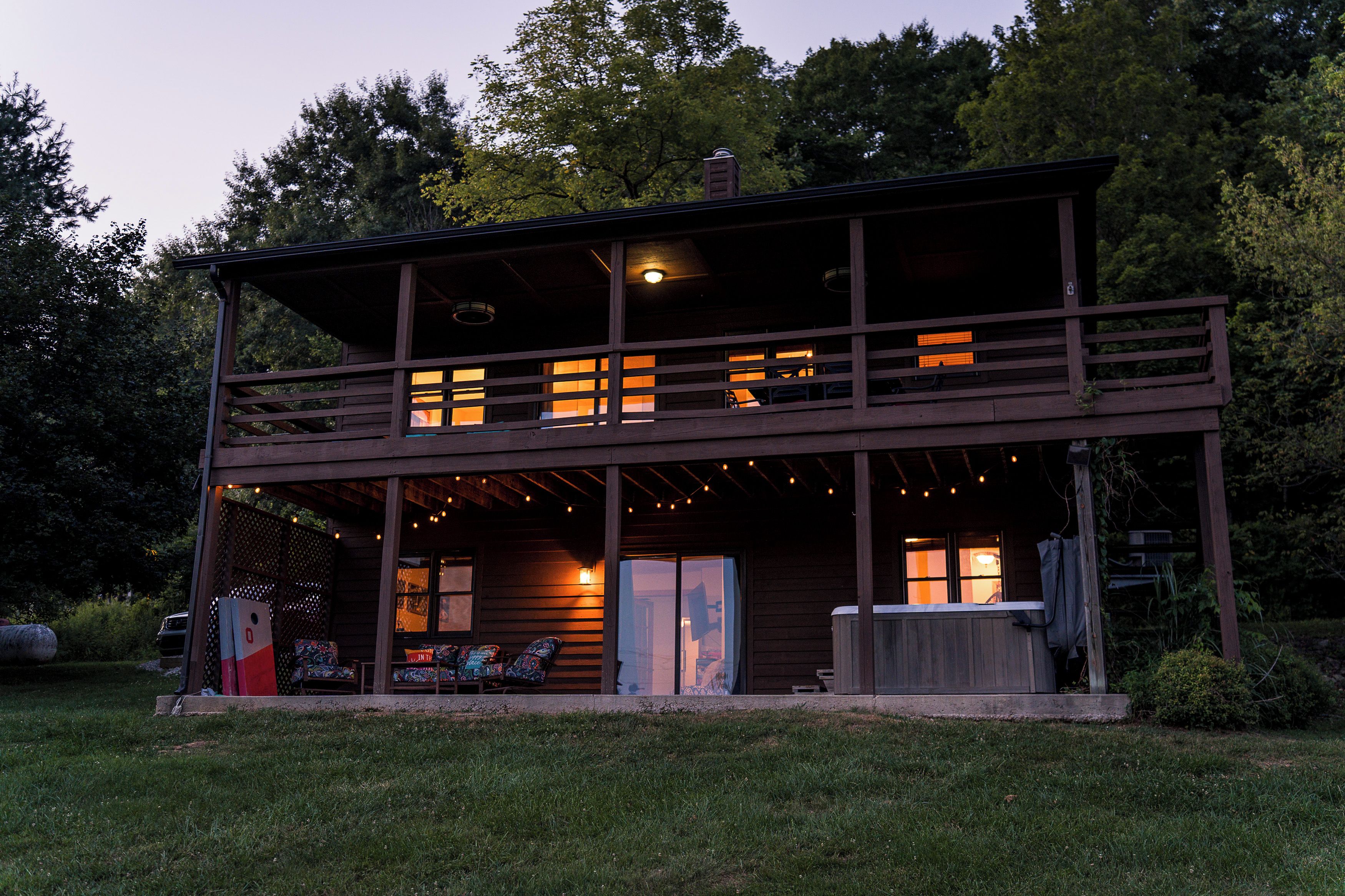 Eine zweigeschossige Holzhütte mit Balkon, Sitzgelegenheit im Freien und überdachter Veranda.