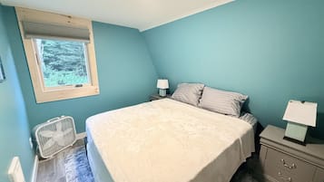 A bedroom with a bed, bedside tables, a window, and a radiator.