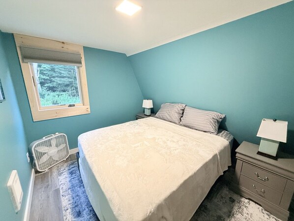 A bedroom with a bed, bedside tables, a window, and a radiator.