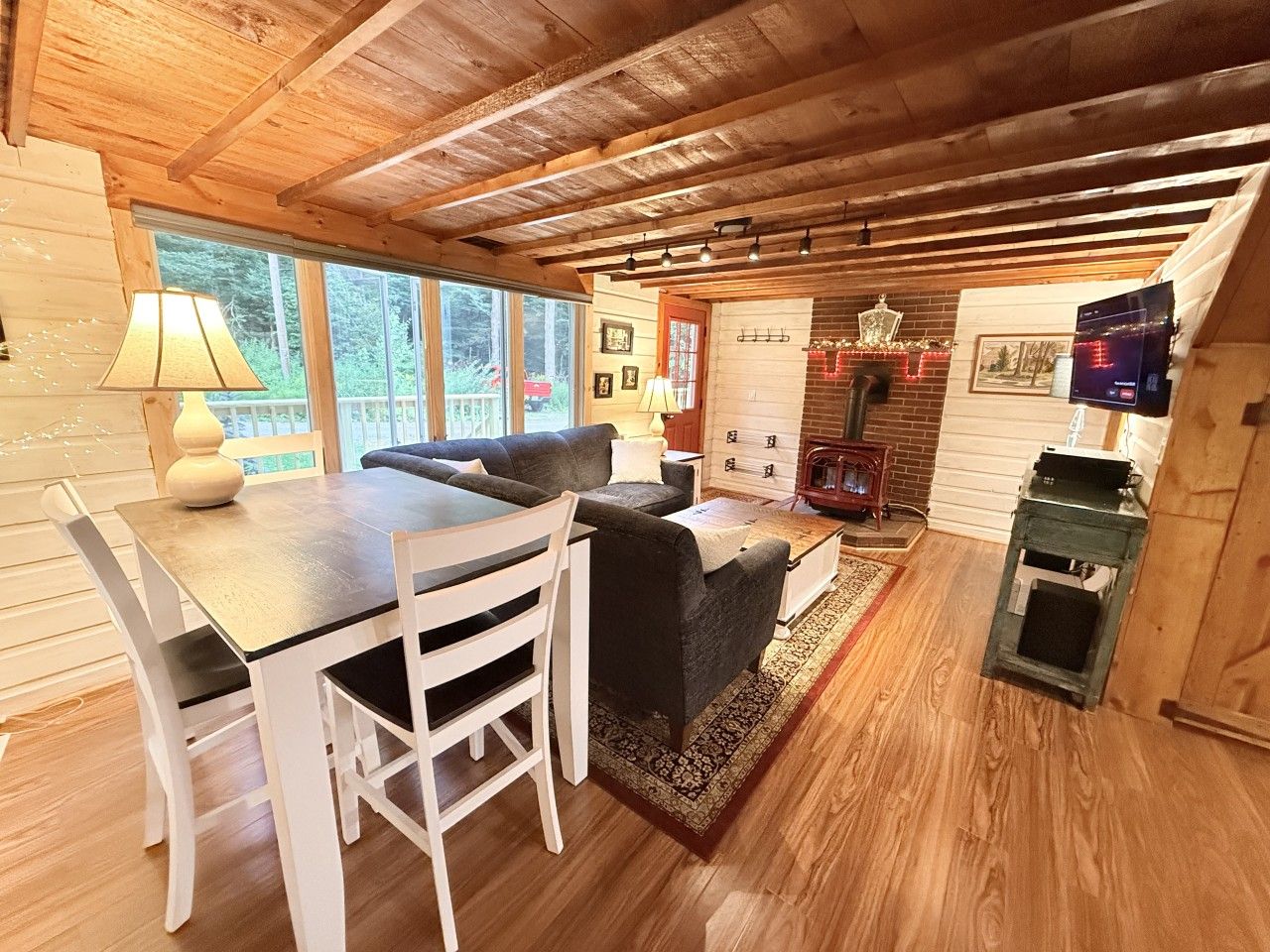 A cozy cabin interior with a dining area, sofa, fireplace, and a television.