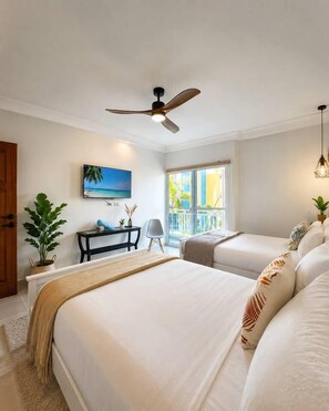 A hotel room with a bed, a desk, a chair, a ceiling fan, a TV, and a window with a view. - Walk to Beach! Modern Luxury & Peace in Cortecito (Punta Cana)