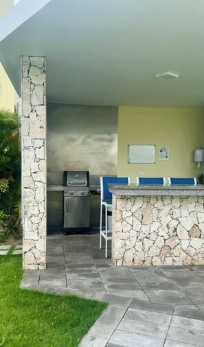 Ein Außenbereich mit Küche, einer Steinwand, einem Grill und einer Theke.
