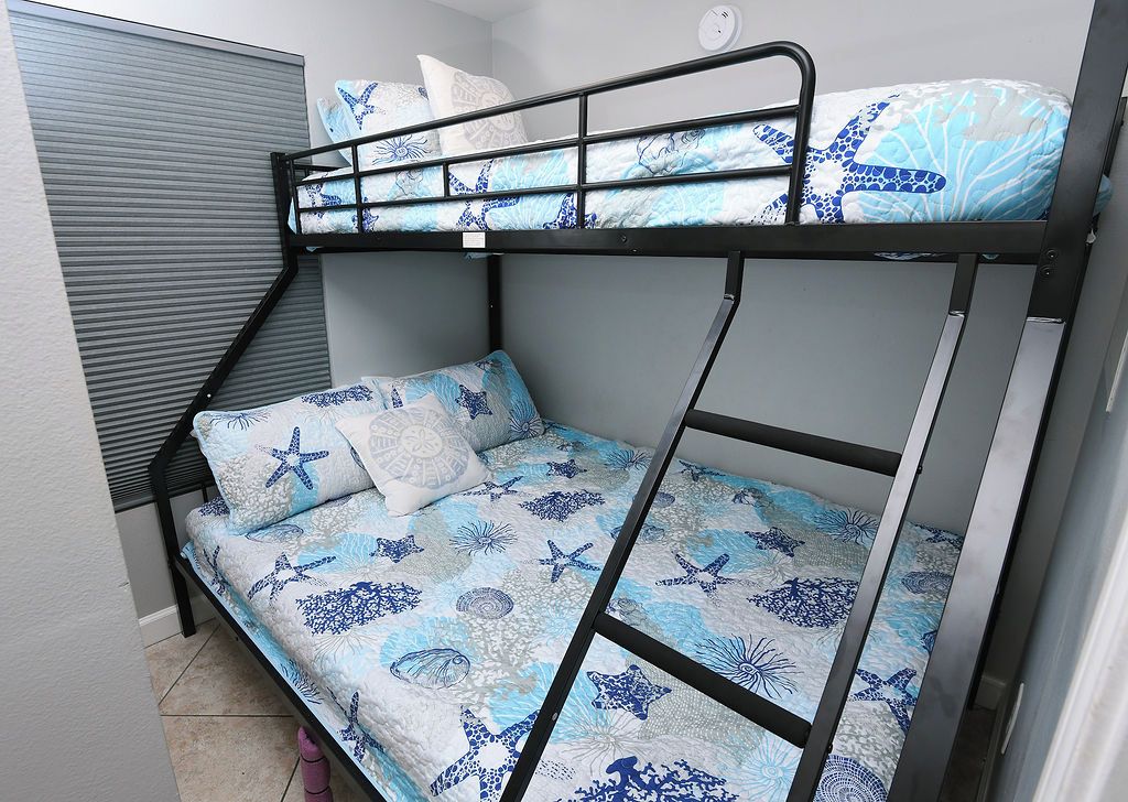 Una cama litera con un edredón estampado, una almohada y una mesita de noche.