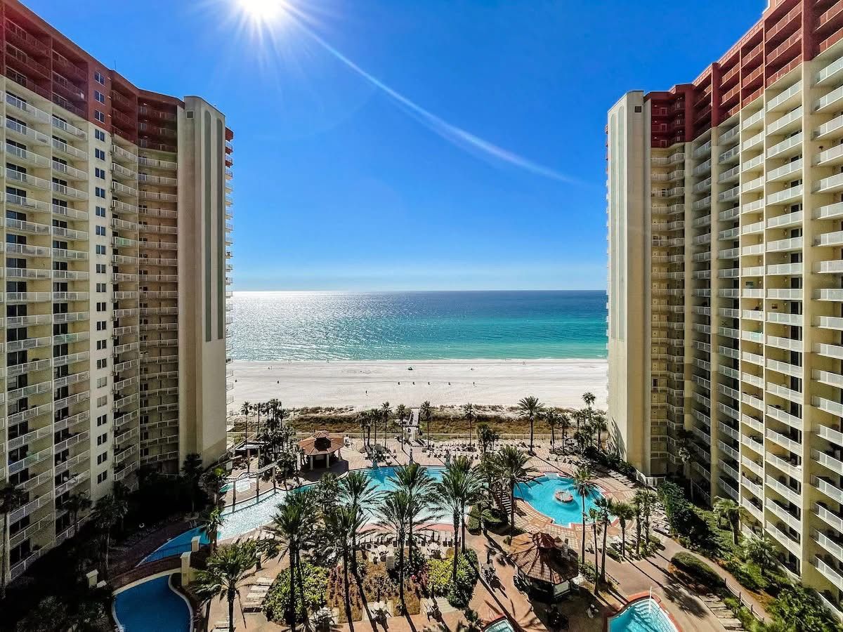 A high-rise hotel with a pool area, beach view, and multiple balconies.