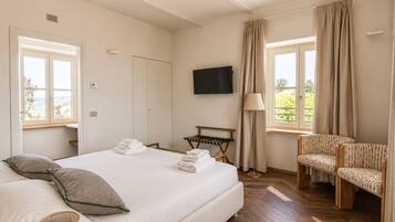 Ein Hotelzimmer mit einem Bett, einem Fernseher, einem Sessel, einer Lampe und einem Fenster mit Vorhängen.