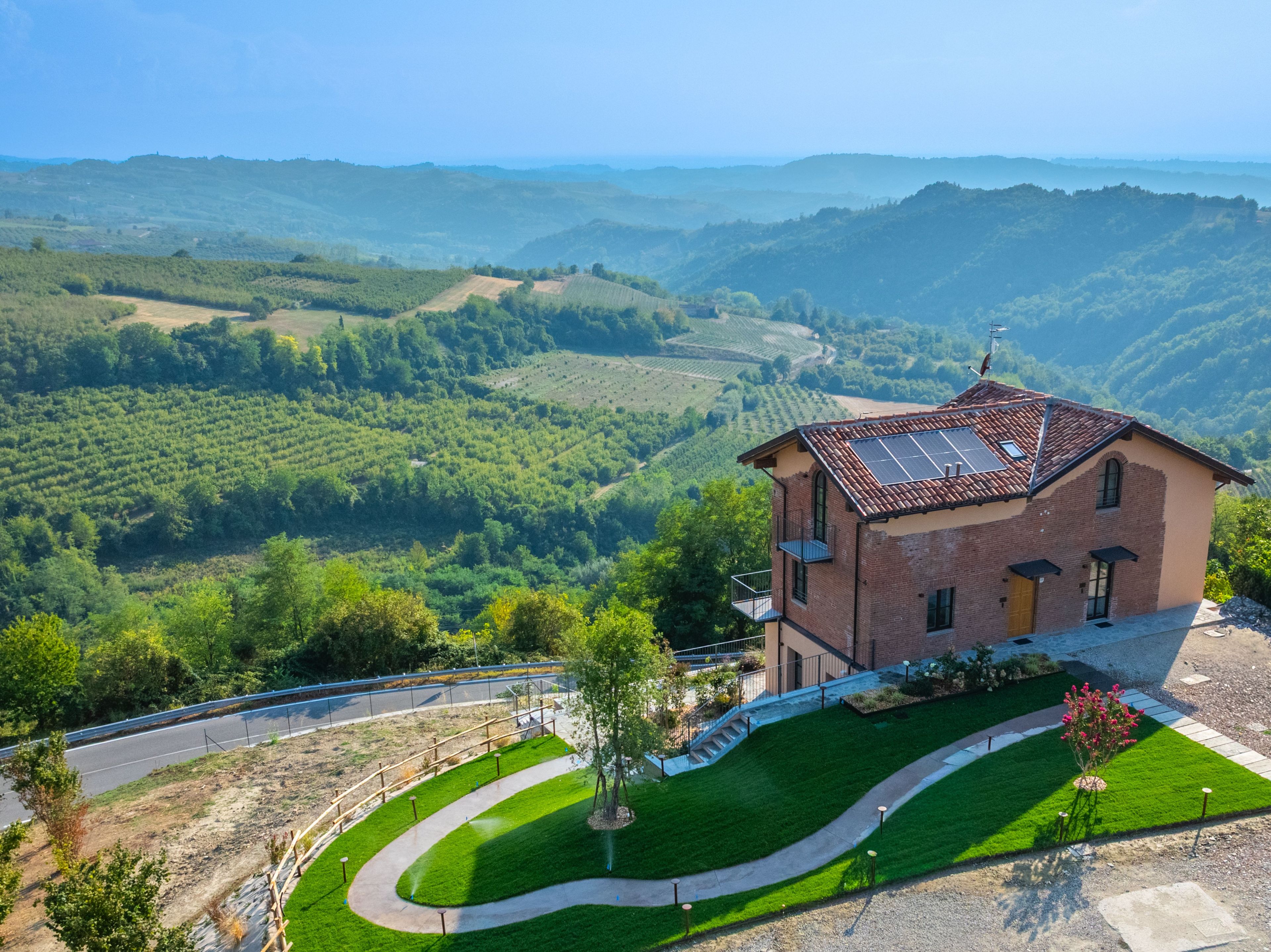 Uma casa com telhado inclinado, painéis solares e vista para um vale.