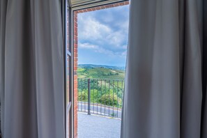 A view from a balcony with a metal railing, overlooking a green landscape and a road. - Bricco Neri - Alba - One Bedroom Apartment, Sleeps 4 (Rodello)