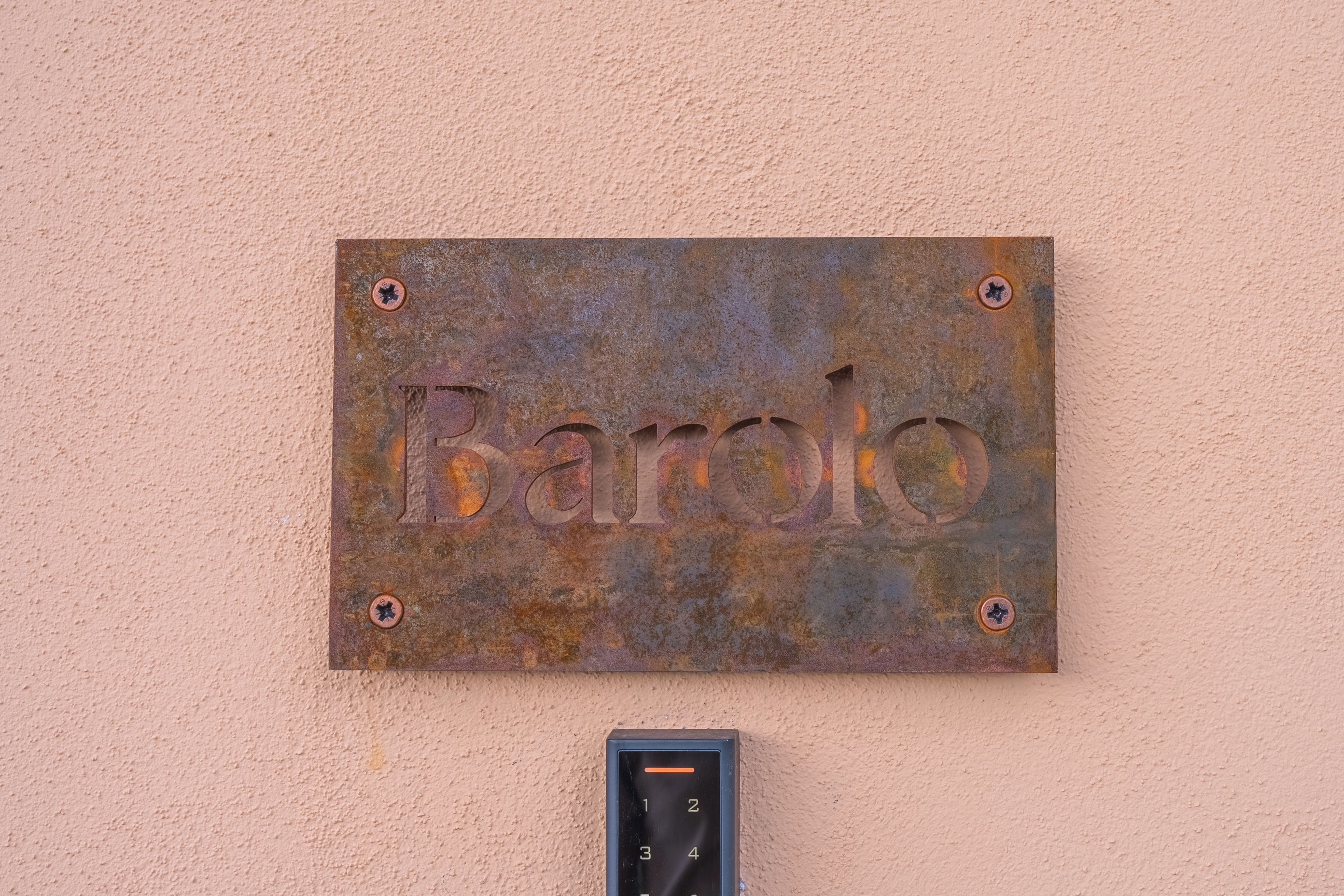 Un cartello di metallo arrugginito con la scritta 'Barolo' fissato a una parete.