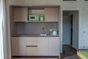 A compact kitchenette with a microwave, kettle, and a sink.