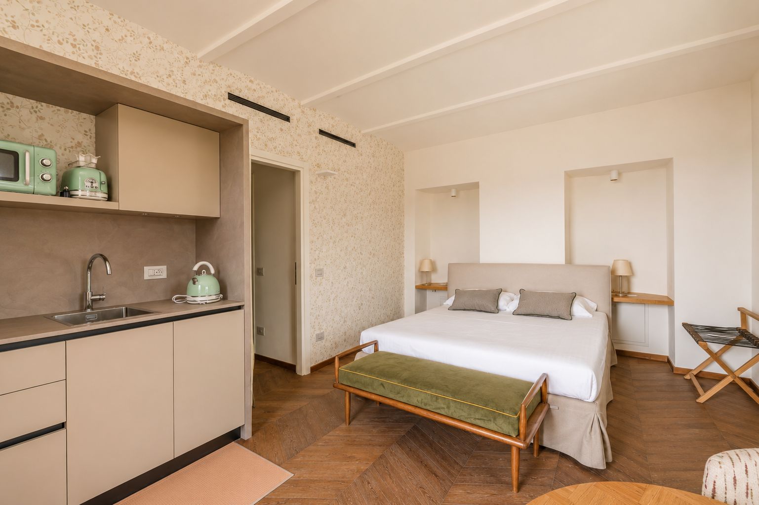 Ein Schlafzimmer mit einem Bett, Nachttischen und einer kleinen Küchenzeile.