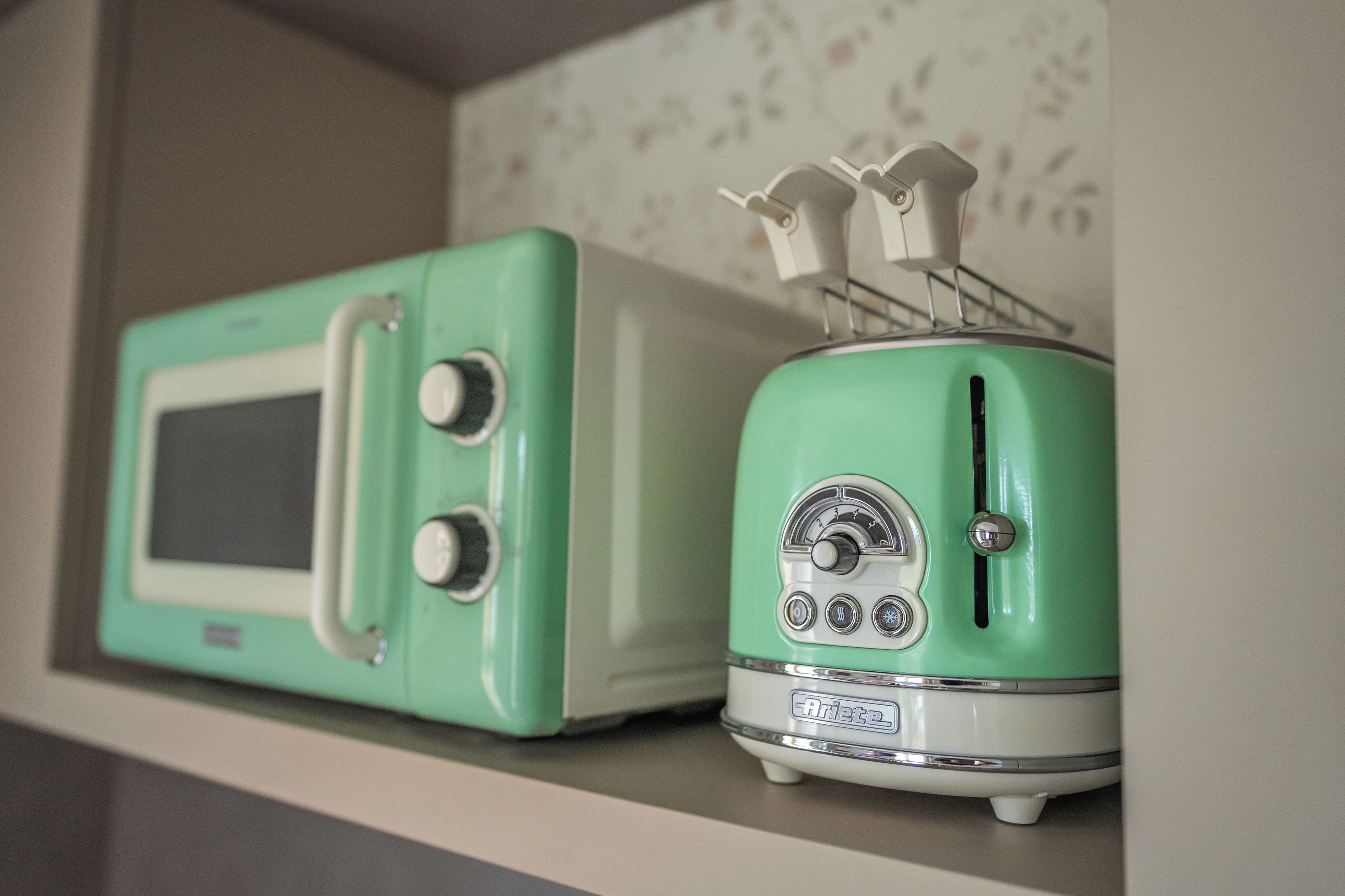 Zwei Vintage-Geräte in Grün, eines mit Bildschirm und Drehreglern, das andere mit Lüfterrad und Tasten, stehen auf einem Regal.
