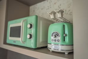 Two vintage green appliances, one with a display screen and knobs, and the other with a dial and buttons, on a shelf.