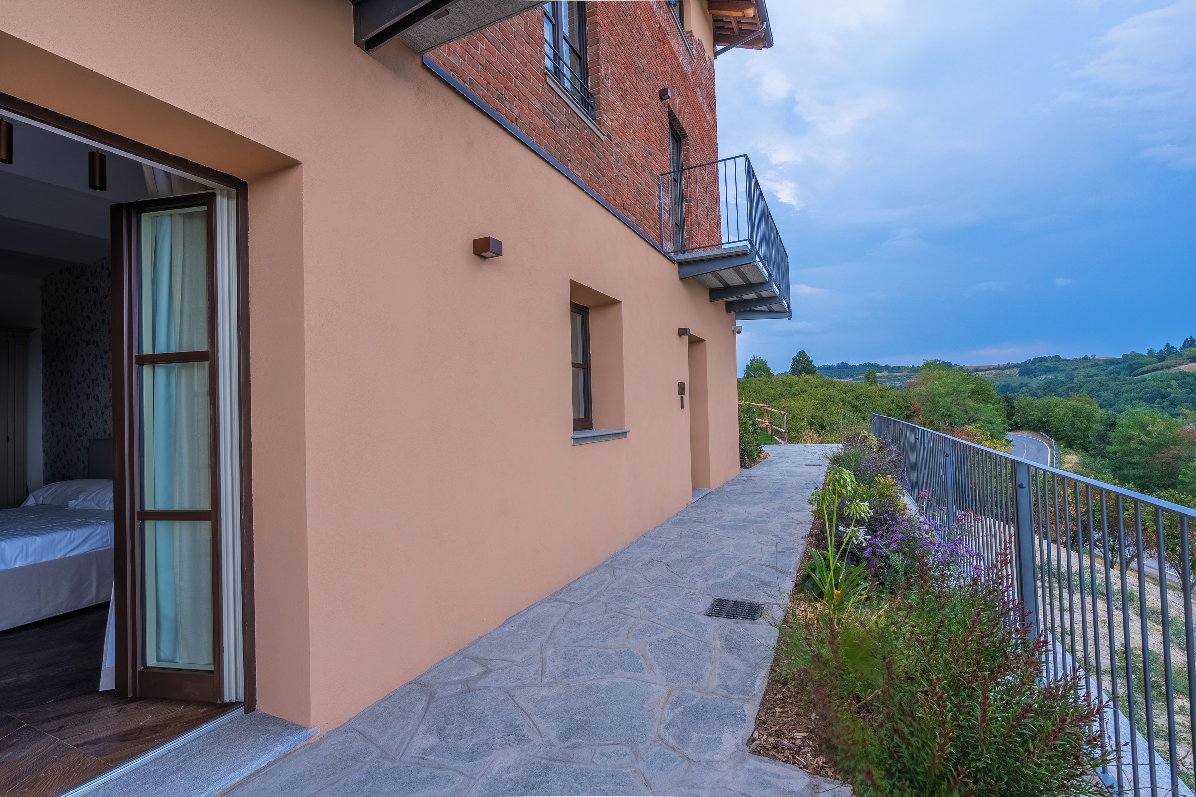 Ein modernes Gebäude mit Balkon, einem Kiesweg und Blick auf die Landschaft.