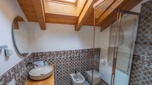 Ein Badezimmer mit einem Holzbadezimmerhocker, einer Toilette und einer Duschkabine.