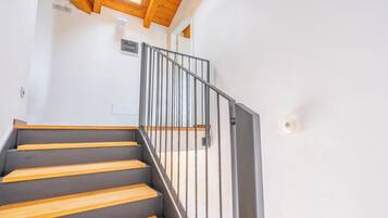 Eine Treppe mit Holzboden und Metallgeländer, die zu einem Raum mit einem Oberlicht führt.