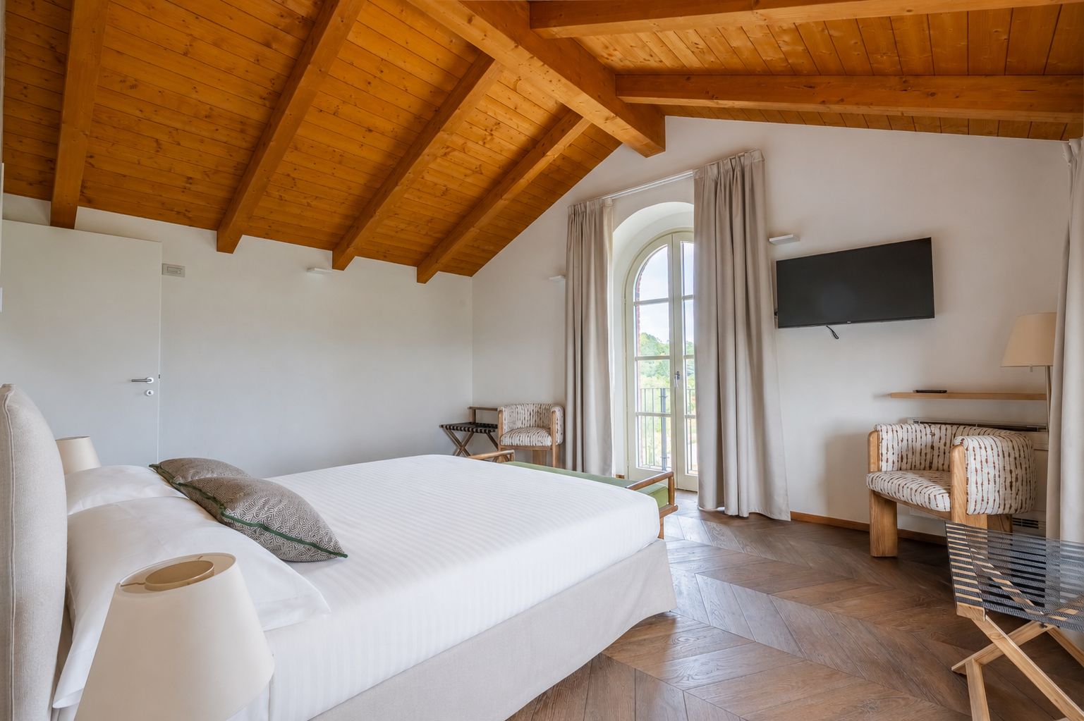 Ein Schlafzimmer mit einem Bett, einem Fernseher, einem Sessel und einem Fenster.