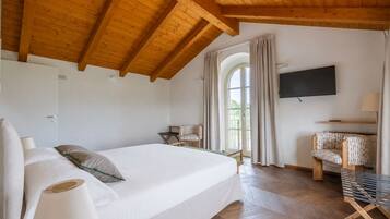 Ein Schlafzimmer mit einem Bett, einem Fernseher, einem Sessel und einem Fenster.