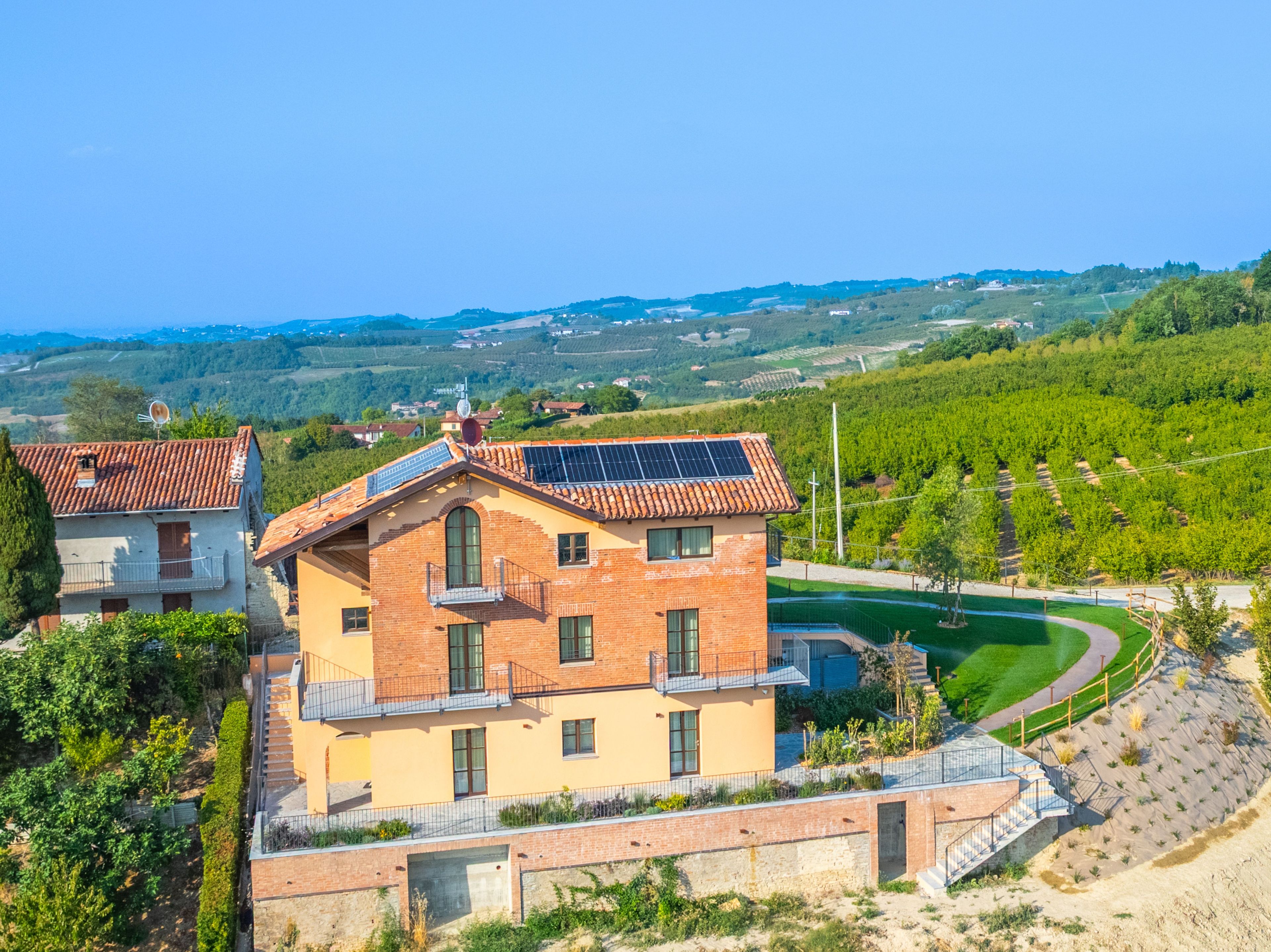 Un bâtiment à deux étages, doté d’un toit en pente, de panneaux solaires et offrant une vue sur un vignoble.