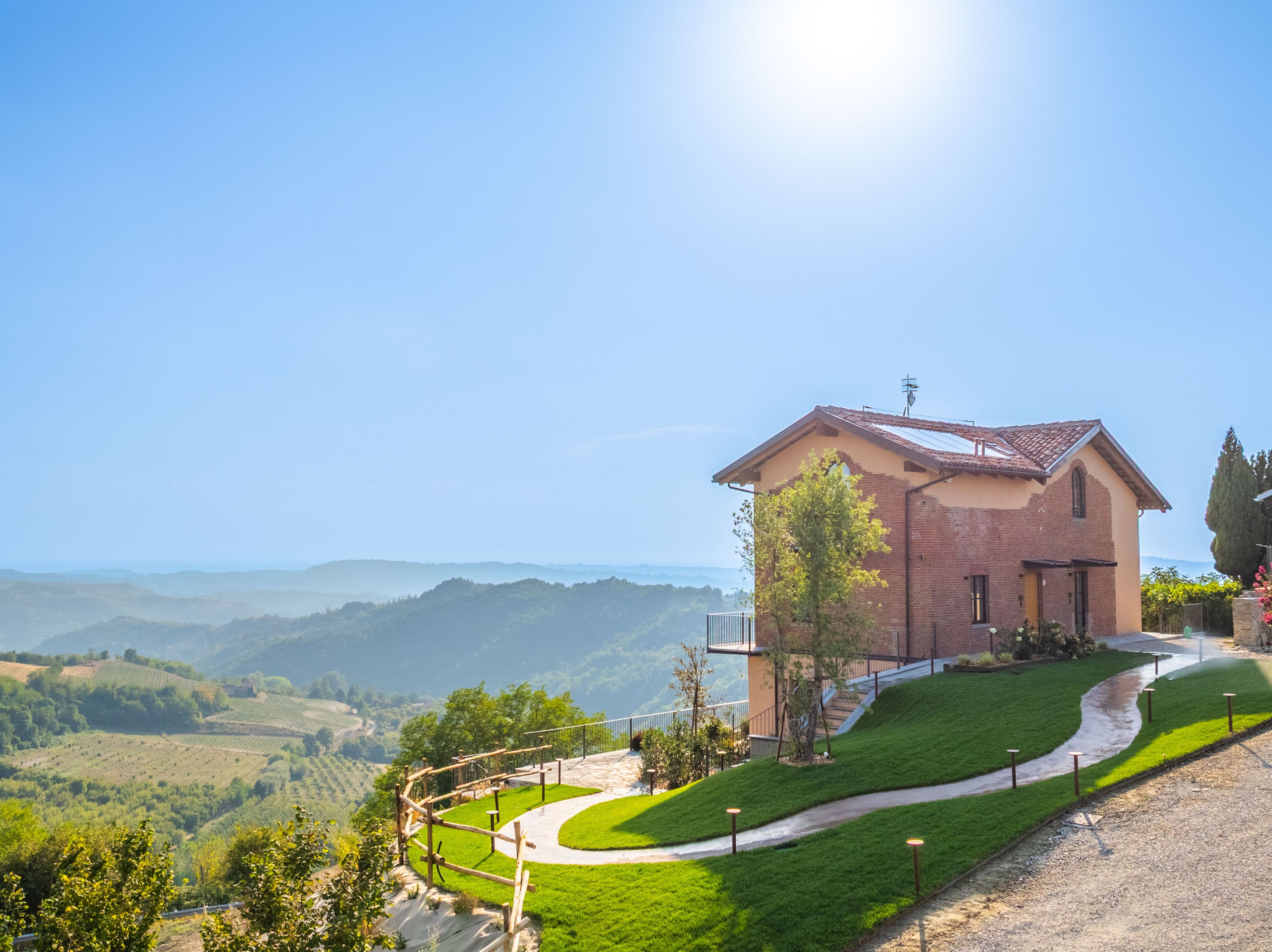 Uma casa com entrada por calçada e vista para colinas.