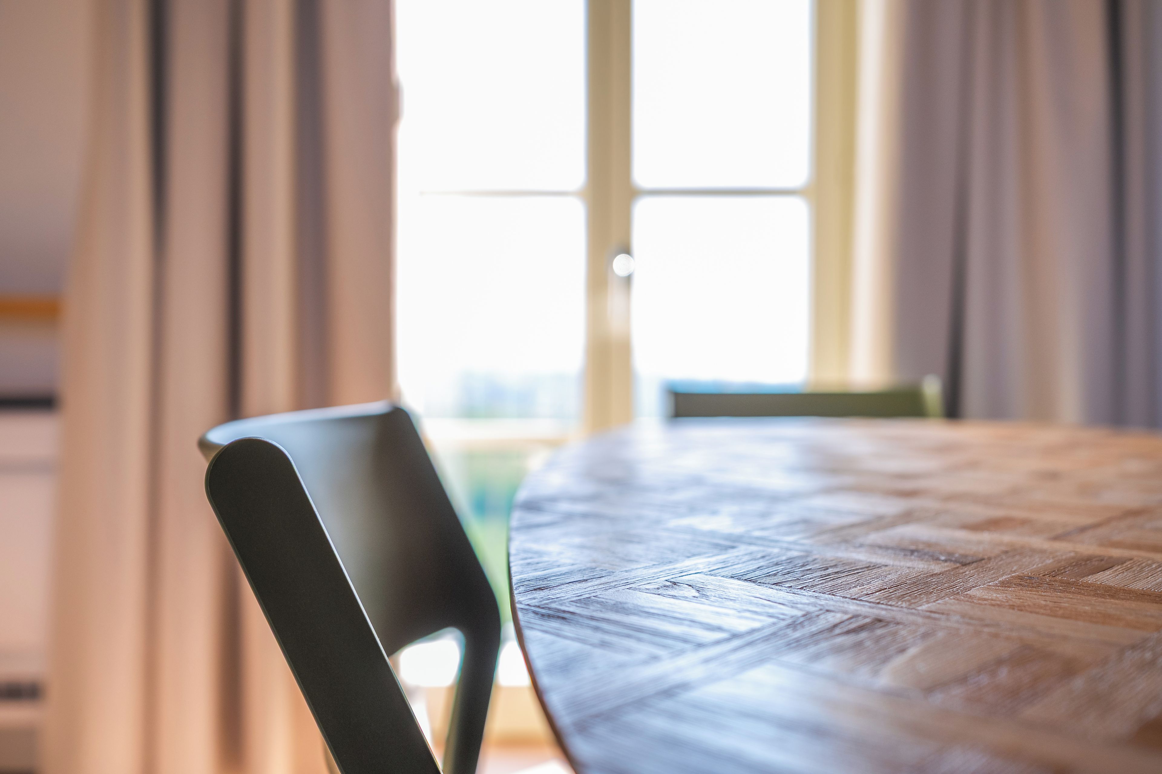 Mesa de jantar com uma cadeira em um quarto com janela e cortinas.