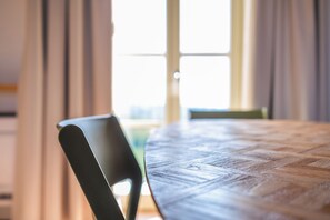 Mesa de jantar com uma cadeira em um quarto com janela e cortinas.