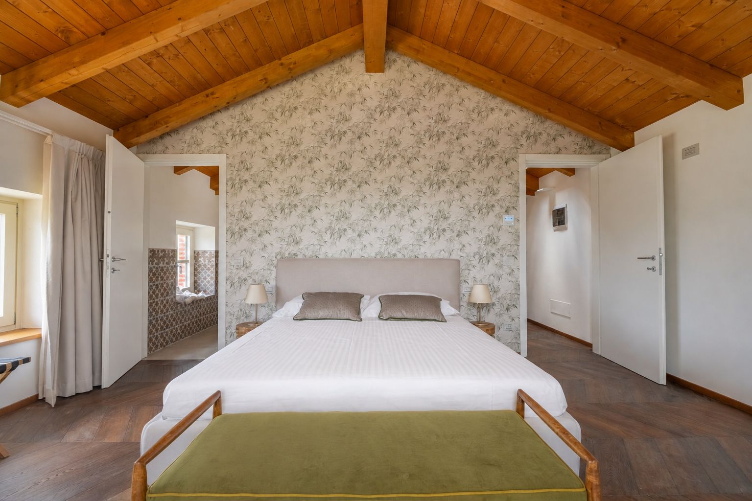 Ein Schlafzimmer mit einem großen Bett, Holzbalkendecke und blumigem Wandpapier.