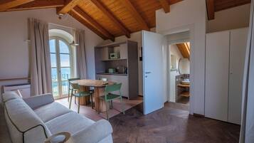 Ein modernes Interieur mit Holzboden, einer Essecke mit Tisch und Stühlen, einer Küchenzeile und einem Badezimmer mit Waschbecken und Spiegel.