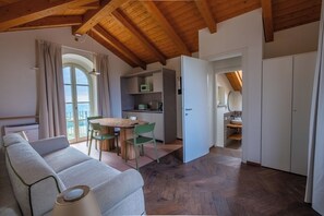 A modern interior with a wooden ceiling, a dining area with a table and chairs, a kitchenette, and a bathroom with a sink and mirror. - Bricco Neri - Monviso (Rodello)