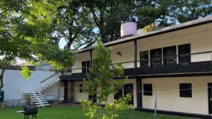 A two-story building with a flat roof, a visible staircase, and a small tree in the yard. - Hotel mg (Palenque)
