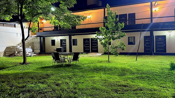 A modern building with a flat roof, a covered outdoor area with a table and chairs, and a staircase leading to an upper level. - Hotel mg (Palenque)