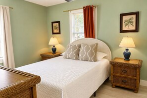 A bedroom with a bed, two bedside tables with lamps, a window with curtains, and two wall-mounted pictures. - Stylish Florida Getaway  Patio & Private Backyard (West Palm Beach)