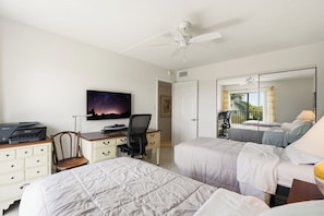 A hotel room with two beds, a desk with a printer, a chair, a ceiling fan, and a large window with a view. - Gulf-Front Views at Dolphin Way | Direct Beach Access | Sleeps 6 | Heated Pool (Bonita Springs)