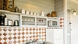 Cocina con gabinetes blancos, un lavamanos y una cafetera.